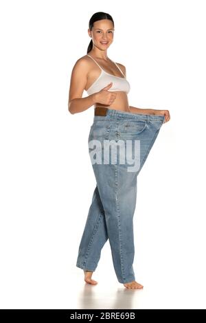Junge schlanke Frau in großen Hosen mit Daumen nach oben Stockfoto