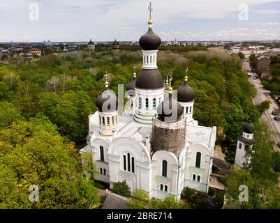 Weiße orthodoxe Kirche unter grünen Bäumen mit Kuppel unter Rekonstruktion Antenne. Johannes der Vorläufer Stockfoto