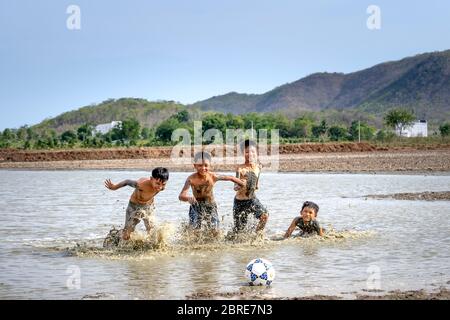 Phan Thiet, Provinz Binh Thuan, Vietnam - 16. Mai 2020: Jungs aus einem kleinen Dorf spielen Fußball im Schlamm, so glücklich und lustig in Phan Thiet, Vietnam Stockfoto