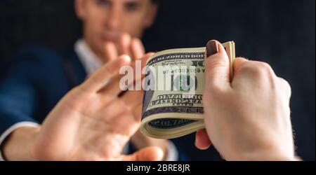 Ein Mann Geschäftsmann in einer Klage lehnt Geld, das in den Händen einer Person, die ein Bestechungsgeld gehalten wird. Konzept von Bestechung und Korruption Stockfoto