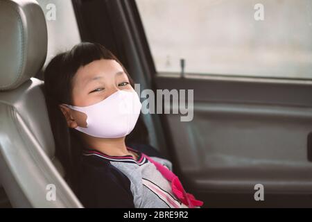 Asiatische kleine Mädchen in einem Gesicht Maske aus einem Autofenster. Hygiene Maske Schutz Coronavirus oder Covid-19 Stockfoto