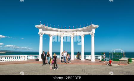 Aluschta, Krim - 15. Mai 2016: Menschen Promenade am Wasser in Krim, Russland. Die berühmte Rotunde 'Resort Aluschta' am Strand. Wunderschönes Pano Stockfoto