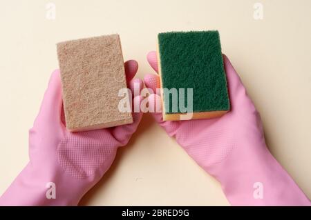 Hände in Gummihandschuhe halten diffuse Schwämme. Kunststoff und Naturschwamm. Stockfoto