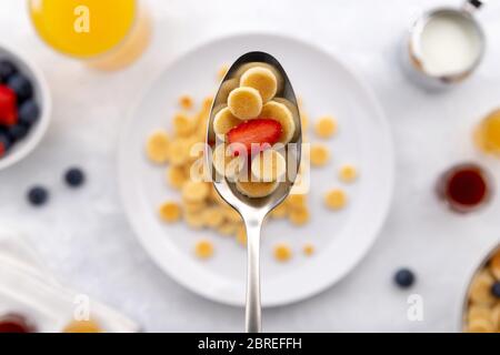 Winziger Mini-Pfannkuchen-Müsli. Hausgemachtes Frühstück mit Himbeeren, Heidelbeeren, Marmelade und Saft auf grauem Hintergrund Stockfoto