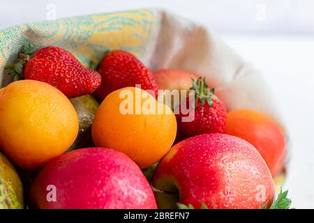 Frisches Obst in einem Bio-Baumwollbeutel auf einem Tisch in der Küche. Mit Äpfeln und Birnen, Aprikosen und Erdbeeren, Zero Waste Trading Konzept. Verbot von Kunststoff Stockfoto