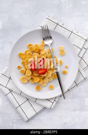 Winziger Mini-Pfannkuchen-Müsli. Hausgemachtes Frühstück mit Himbeeren, Marmelade und Saft auf grauem Hintergrund Stockfoto