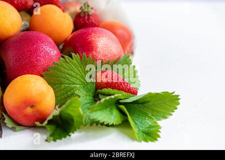 Frisches Obst in einem Bio-Baumwollbeutel auf einem Tisch in der Küche. Mit Äpfeln und Birnen, Aprikosen und Erdbeeren, Zero Waste Trading Konzept. Verbot von Kunststoff Stockfoto