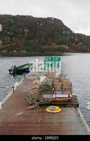 Kleines Creel-Fischerboot, das in Plockton festgemacht ist, mit Kreellen, die auf dem Steg daneben angelegt sind. Stockfoto