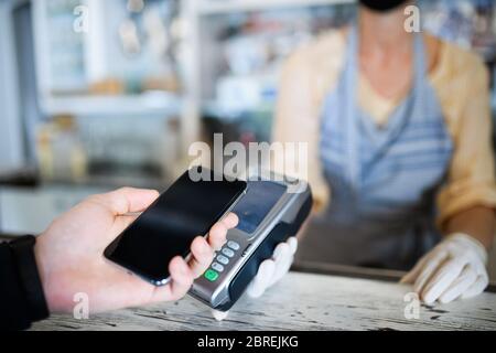 Kontaktloses Bezahlen mit Smartphone, Café nach Sperrung geöffnet. Stockfoto