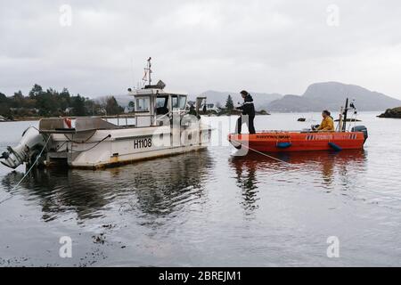 Fischer, die an Bord eines Bootes von einem Tender auf Loch Carron im kleinen Fischerdorf Plockton in den schottischen Highlands sind. Stockfoto