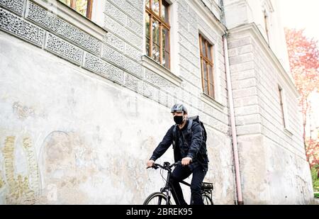 Lieferung Mann Kurier mit Gesichtsmaske und Fahrrad Radfahren in der Stadt. Stockfoto