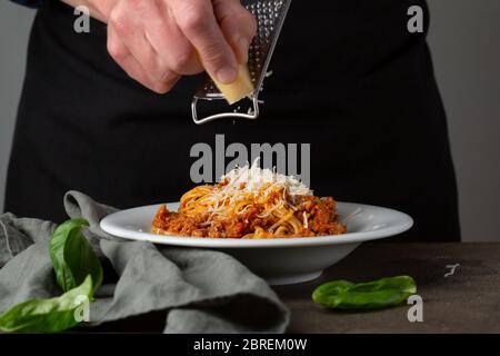 Bolognese Pasta. Von Hand geriebenem Käse auf Spaghetti Stockfoto