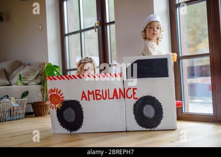 Zwei kleine Kinder mit Arztuniformen zuhause, spielend. Stockfoto