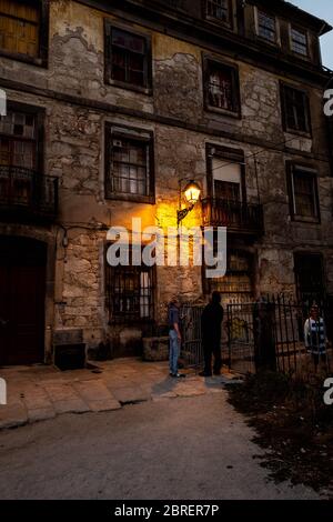 Altes, zerstörtes Gebäude im alten Porto bei Einbruch der Dunkelheit mit einem Lampenposten. Stockfoto