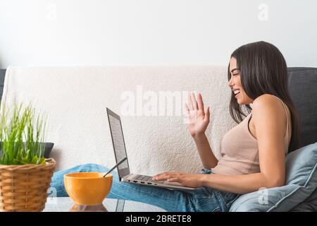 Junge Frau macht Videoanruf sitzen auf dem Sofa - Happy girl Spaß dabei Videokonferenz mit Familie und Freunden Stockfoto