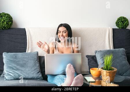 Junge Frau macht Videoanruf sitzen auf dem Sofa - Happy girl Spaß dabei Videokonferenz mit Familie und Freunden Stockfoto