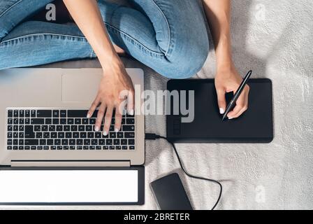 Grafikdesignerin Frau smart arbeiten am Computer zu Hause - Junge weibliche Zeichnung mit interaktivem Stift und Laptop im Bett Stockfoto