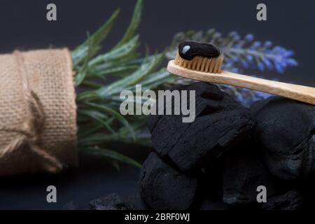 Natürliche Zahnpasta Aktivkohle und Bambus Zahnbürste auf schwarzem Hintergrund. Konzept ohne Verschwendung. Stockfoto