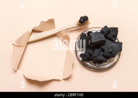 Natürliche Zahnpasta Aktivkohle in Glas und Bambus Zahnbürste auf Kamelfarbe Hintergrund. Konzept ohne Verschwendung. Stockfoto