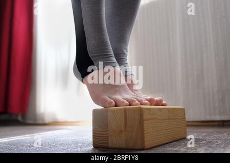 Frau macht Übung für starken Fuß mit hölzernen Requisiten. Stockfoto