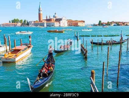 Venedig, Italien - 18. Mai 2017: Gondeln fahren in der Nähe des Markusplatzes in Venedig. Romantische touristische Wasserfahrt durch Venedig im Sommer. Landschaftlich schöne Aussicht auf c Stockfoto
