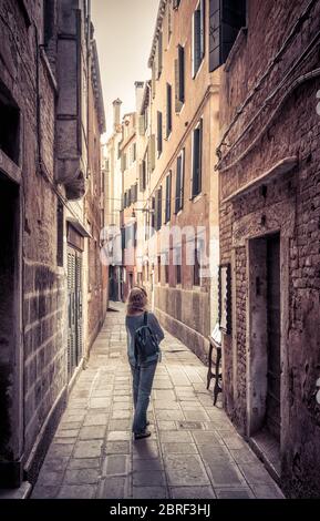 Girl Tourist ist in einer engen Straße in Venedig, Italien. Reisende Spaziergänge in Venedig. Alte Architektur und historische Orte in Venedig. Junge Frau reist t Stockfoto