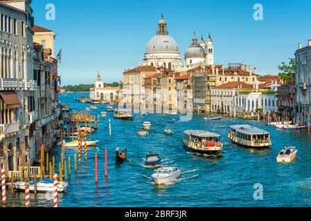 Venedig, Italien - 18. Mai 2017: Verkehrsverkehr auf dem Canal Grande in Venedig, Italien. Die Kirche Santa Maria della Salute in der Ferne. Grand Canal ist o Stockfoto