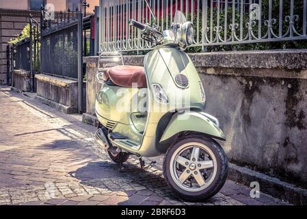 Roller auf einer alten Straße geparkt. Roller oder Motorrad ist einer der beliebtesten Verkehrsmittel in Europa. Foto im Vintage-Stil. City-Szene mit grünem Retro Stockfoto