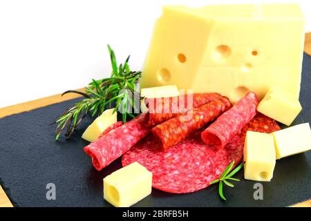 Emmentaler französischer Käse, Chorizo, Salami und grüne Kräuter auf der Tapas-Tafel Nahaufnahme. Fast Food für einen Snack. Stockfoto