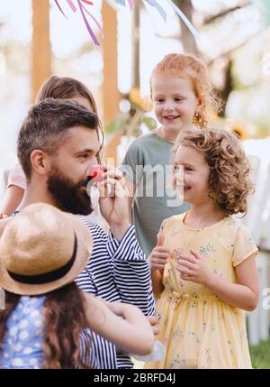 Mann mit kleinen Kindern im Sommer im Garten auf dem Boden sitzend, spielend. Stockfoto