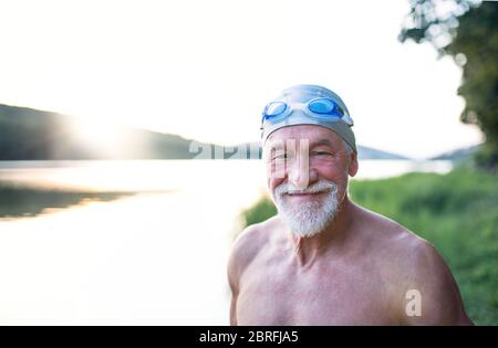 Älterer Mann in Badeanzug, der vor dem Schwimmen am See steht. Stockfoto