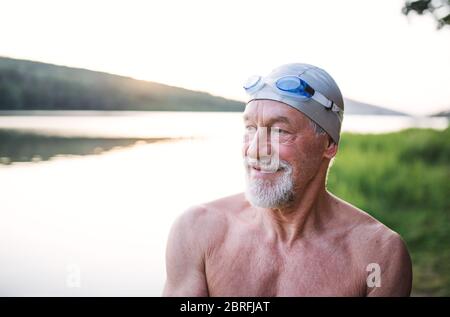 Älterer Mann in Badeanzug, der vor dem Schwimmen am See steht. Stockfoto