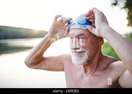 Älterer Mann in Badeanzug, der vor dem Schwimmen am See steht. Stockfoto