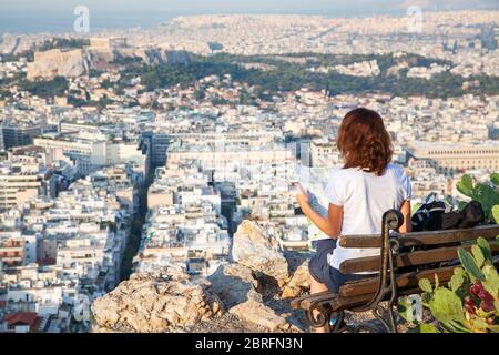 Frau mit einer Karte auf dem Lycabettus-Hügel, dem höchsten Punkt der Stadt mit Blick auf Athen mit der Akropolis - Weltreisender Stockfoto