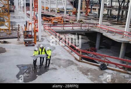 Eine Draufsicht der Gruppe von Ingenieuren mit Bauplänen auf der Baustelle. Stockfoto