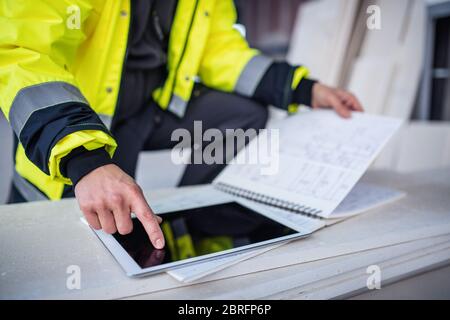 Unerkennbarer Mann Ingenieur auf der Baustelle, hält Tablet mit Blaupausen. Stockfoto