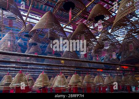 Weihrauchspulen hängen von der Decke, mit Gebeten auf roten Etiketten, die an ihnen angebracht sind, im man Mo Tempel, Hongkong, China, Asien Stockfoto