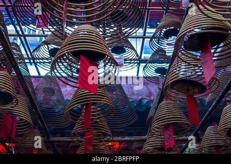 Weihrauchspulen hängen von der Decke, mit Gebeten auf roten Etiketten, die an ihnen angebracht sind, im man Mo Tempel, Hongkong, China, Asien Stockfoto