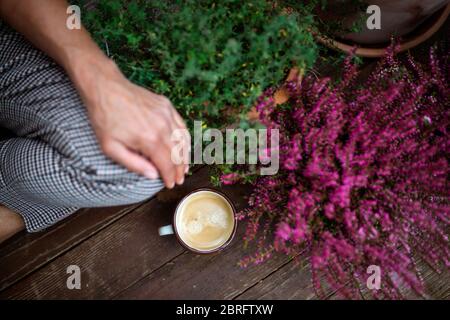 Mittelteil der Frau mit Kaffee im Freien auf der Terrasse sitzen, ausruhen. Stockfoto