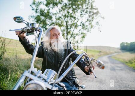 Ein älterer Mann, der mit dem Motorrad auf dem Land unterwegs ist. Stockfoto