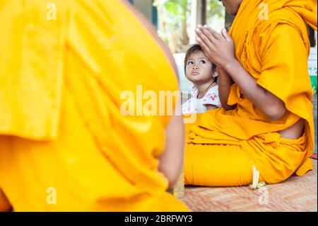 Ein junges Mädchen schaut auf einen buddhistischen Mönch. Vipassana Dhura Buddhistisches Zentrum, Udong, Provinz Kampong Speu, Kambodscha, Südostasien Stockfoto