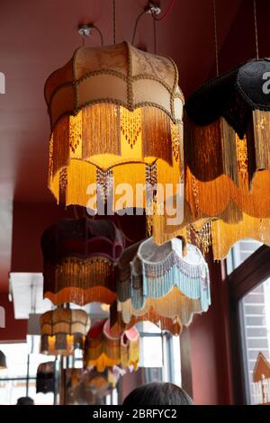 Ein textiler Kronleuchter, der durch gelbes Licht von der Decke hängt. Stockfoto
