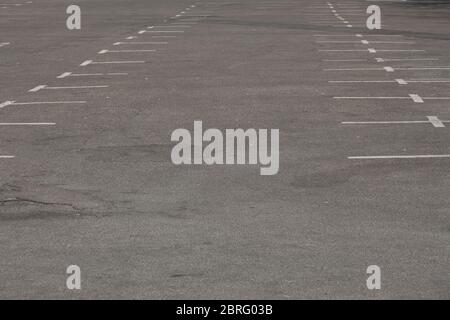 Alte, schmutzige und verblassende weiße Markierungen auf einem leeren Parkplatz Stockfoto