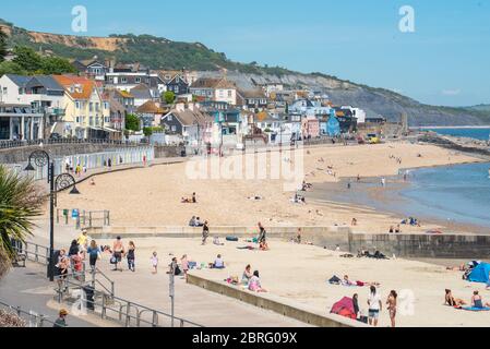 Lyme Regis, Dorset, Großbritannien. Mai 2020. UK Wetter: Einheimische und Familien genießen die heiße Nachmittagssonne im Badeort Lyme Regis. Obwohl die Parkplätze geschlossen blieben, war der Strand an diesem Nachmittag voller mit verantwortungsbewussten Strandbesuchern, die soziale Distanz aufrechterhalten, während sie die Sonne aufnässten. Kredit: Celia McMahon/Alamy Live News Stockfoto