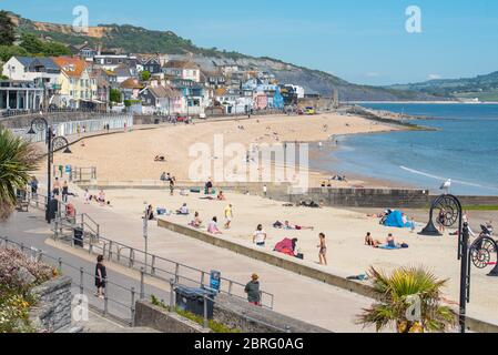 Lyme Regis, Dorset, Großbritannien. Mai 2020. UK Wetter: Einheimische und Familien genießen die heiße Nachmittagssonne im Badeort Lyme Regis. Obwohl die Parkplätze geschlossen blieben, war der Strand an diesem Nachmittag voller mit verantwortungsbewussten Strandbesuchern, die soziale Distanz aufrechterhalten, während sie die Sonne aufnässten. Kredit: Celia McMahon/Alamy Live News Stockfoto