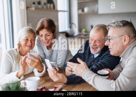 Gruppe von älteren Freunden zu Hause, mit Smartphones. Stockfoto