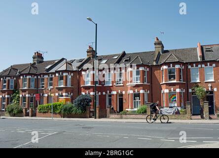 Ein Radsportler geht an einer Terrasse mit gut gepflegten viktorianischen Häusern in twickenham, middlesex, england vorbei Stockfoto