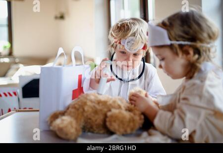 Zwei kleine Kinder mit Arztuniformen zuhause, spielend. Stockfoto