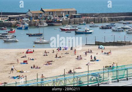 Lyme Regis, Dorset, Großbritannien. Mai 2020. UK Wetter: Einheimische und Familien genießen die heiße Nachmittagssonne im Badeort Lyme Regis. Obwohl die Parkplätze geschlossen blieben, war der Strand an diesem Nachmittag voller mit verantwortungsbewussten Strandbesuchern, die soziale Distanz aufrechterhalten, während sie die Sonne aufnässten. Kredit: Celia McMahon/Alamy Live News Stockfoto