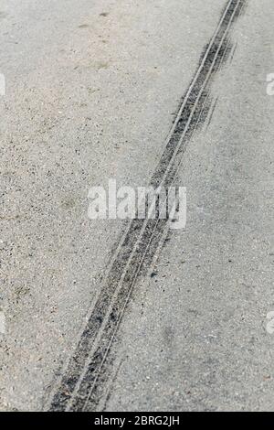 Sonnenlichtscheinte Reifenabrollmarkierung auf der Landstraße. Metapher ländlichen Verkehrsunfälle, Unfallszene. Stockfoto